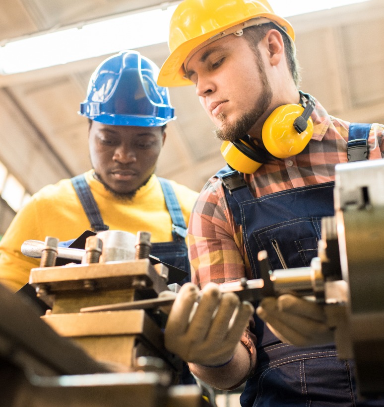two men in hard hats machining parts