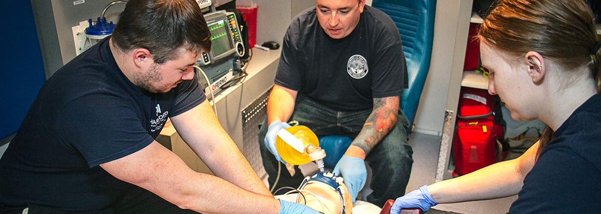 three paramedic students working on dummy in an ambulance
